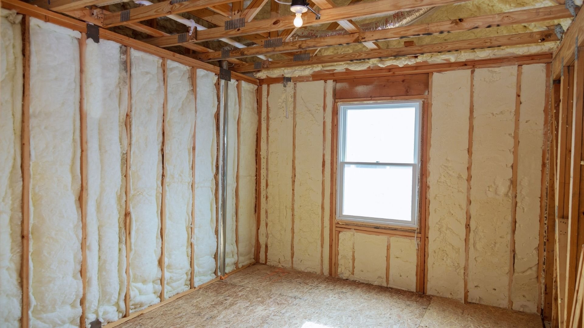 Unfinished wooden framed room with insulation batts and window under construction